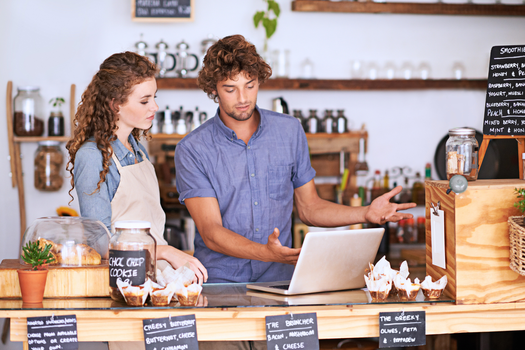 Small business owners reviewing finances at a local café, exploring SBA 7(a) loan options to support operations, working capital, or business expansion.