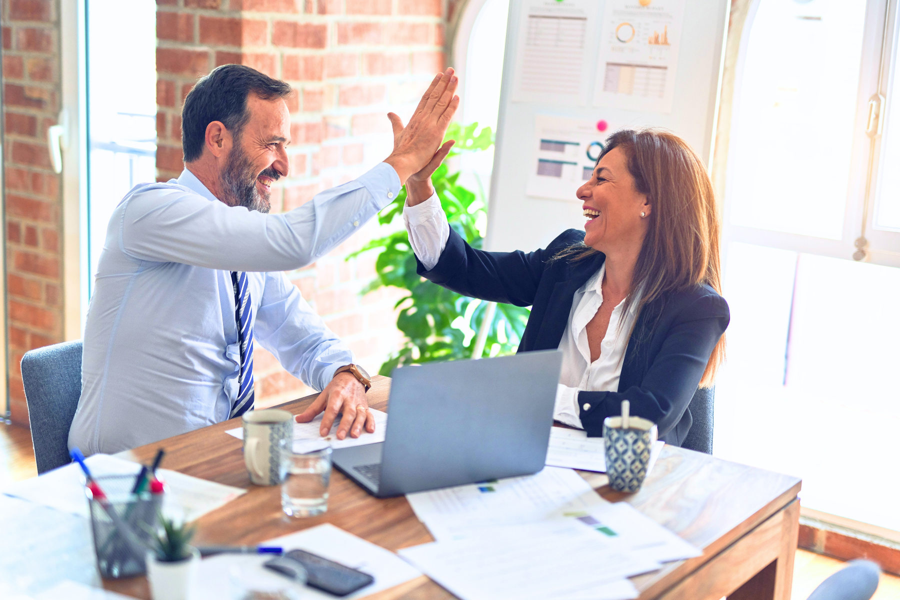Two business professionals celebrating loan approval success, symbolizing the positive impact of SBA 7(a), SBA 504, and SSBCI funding on small business growth and financial empowerment.